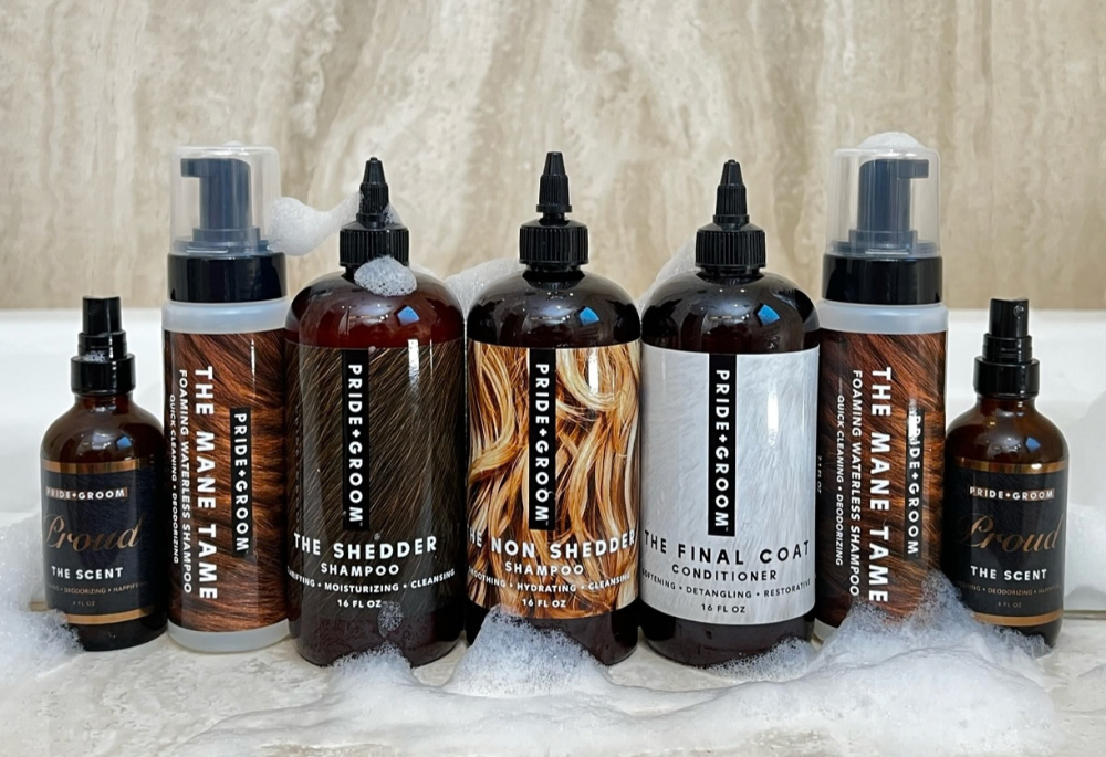 A set of six Pidiroom haircare products arranged on a marble surface with fake foam. The products include various shampoos, conditioners, and scents in amber bottles and pump bottles with black caps.